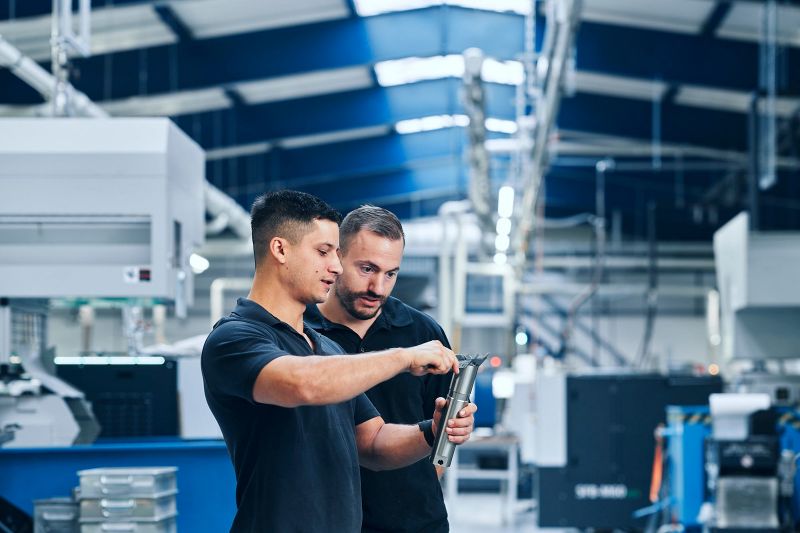 Zwei Mitarbeiter messen gemeinsam ein Präzisionsteil