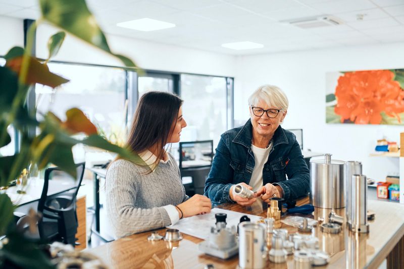 Zwei Mitarbeiterinnen im Büro mit Präzisionsteilen